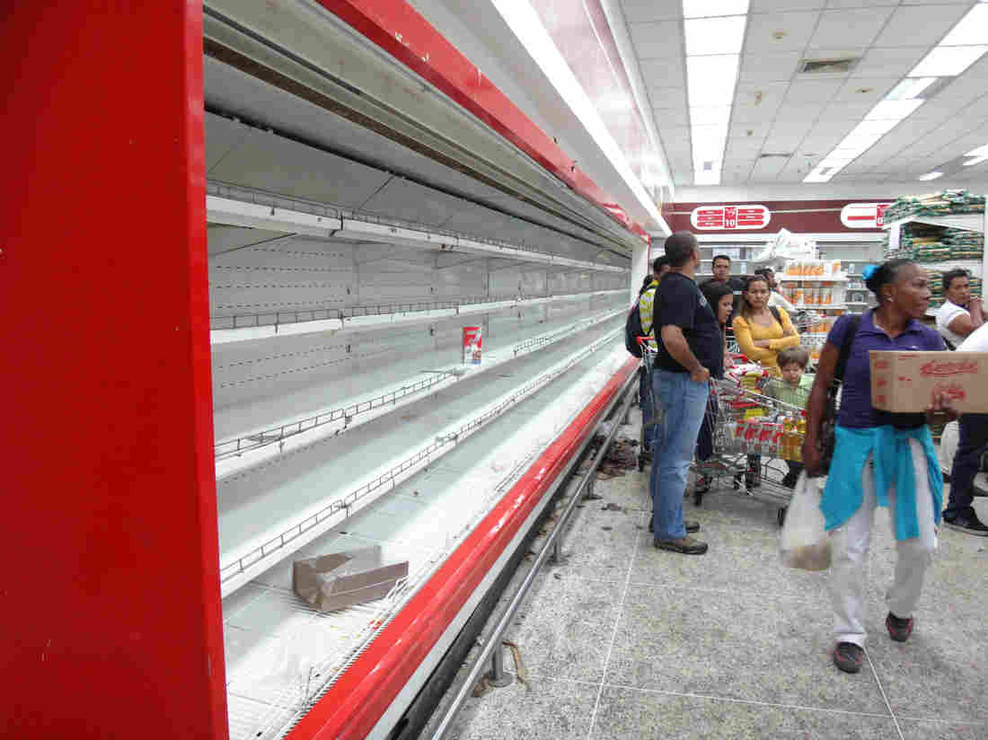 Empty shelves, like these at a supermarket in Caracas, are a common sight in Venezuela. People can shop only on designated days at government-run stores. They're limited in what they can buy and must undergo fingerprint scanning to prove their identity.