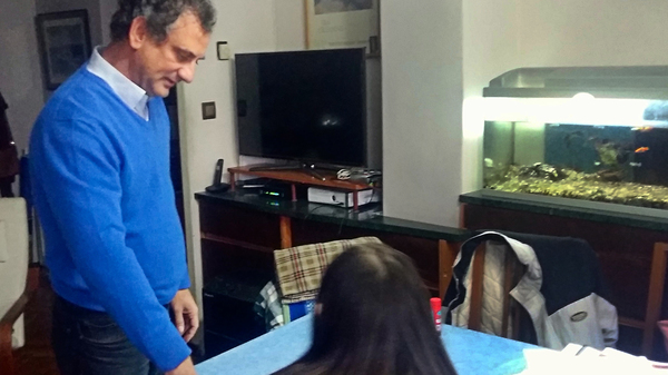 Camilo Jené, 51, watches as his daughter Clara, 14, does her homework at their dining table. She refuses to do homework on weekends now.